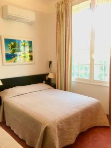 a bedroom with a large bed and a window at Hotel des Mimosas in Juan-les-Pins