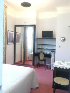 a bedroom with a bed and a desk with a mirror at Hotel des Mimosas in Juan-les-Pins