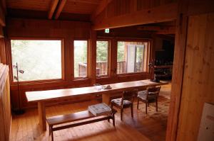 a large wooden table in a room with windows at Miyajima Breeze in Hatsukaichi