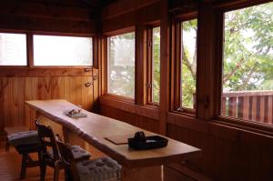 uma mesa de madeira num quarto com janelas em Miyajima Breeze em Hatsukaichi