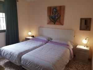 イスナハルにあるCortijo de la Cruzのベッドルーム1室(紫のシーツとランプ2つが備わる大型ベッド1台付)