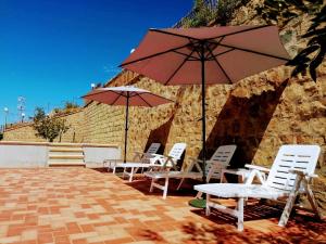 a group of chairs and tables with umbrellas on a patio at Villa Verde in Cefalù