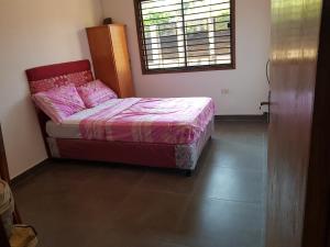 a bedroom with a bed with pink sheets and a window at Casa Naranja in San Lorenzo