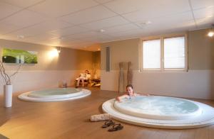 un ragazzo steso in una grande vasca in bagno di SOWELL HOTELS Mont Blanc et SPA a Saint-Gervais-les-Bains