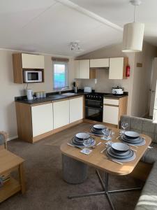 a kitchen with a table with plates on it at Gold Plus 6 Berth Caravan in NEW BEACH with parking WiFi and decking in Dymchurch