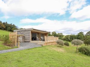 une petite cabine avec une terrasse dans un champ dans l'établissement Meadow Lodge, à Corwen