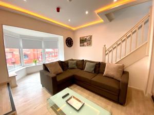 a living room with a brown couch and stairs at Princess Theatre Beach View Apartments in Blackpool