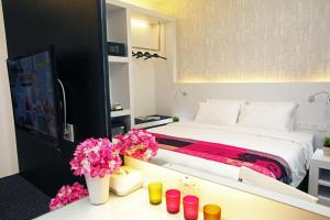 a bedroom with a bed and flowers on a counter at Cairnhill Hotel Kuala Lumpur in Kuala Lumpur