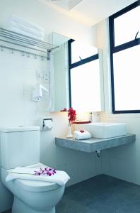 a white bathroom with a toilet and a sink at Cairnhill Hotel Kuala Lumpur in Kuala Lumpur