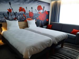 
a bed room with two beds and a painting on the wall at Novotel Ieper Centrum in Ieper
