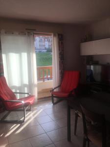 ein Wohnzimmer mit 2 Stühlen, einem Tisch und einem Fenster in der Unterkunft Studio 102 Les Sandia in Valberg