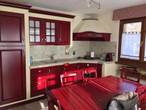 uma cozinha com armários vermelhos e uma mesa de jantar vermelha em House le Betulle em Sauze dʼOulx