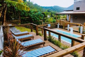 a deck with lounge chairs and a swimming pool at Pousada Makani in Praia do Rosa