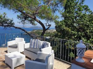 grupa krzeseł siedzących na balkonie z widokiem na ocean w obiekcie L'Incanto Suites Ischia w mieście Ischia
