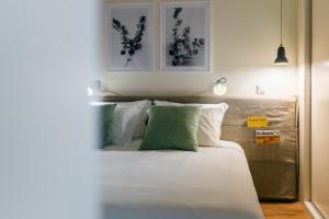 um quarto com uma cama com almofadas brancas e verdes em Three House Hotel em Funchal