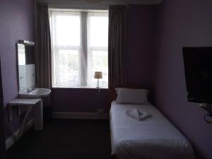 a bedroom with a bed and a window and a sink at LSO Guest House in Dumfries