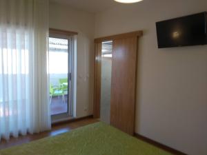 a bedroom with a television and a sliding glass door at Alegria Downtown Apartments in Porto