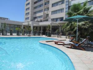 科皮亞波的住宿－夏加爾酒店，一座带椅子和遮阳伞的游泳池位于大楼旁