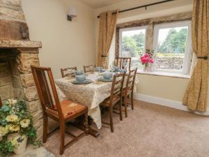 comedor con mesa, sillas y chimenea en Hill Top Cottage, en Keighley