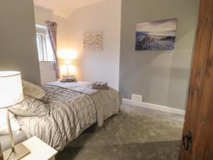 a bedroom with a bed and a lamp on a table at Hill Top Cottage in Keighley