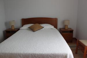 a bedroom with a bed with two nightstands and two lamps at Casa do Almograve in Almograve