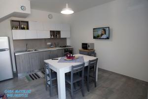 a kitchen with a white table and chairs and a refrigerator at Casa Matilde in Calasetta