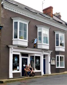 two people sitting in the window of a store at The Bear Bread Bakery, boutique en-suite rooms with breakfast in the Bakery, in the heart of Colyton in Colyton