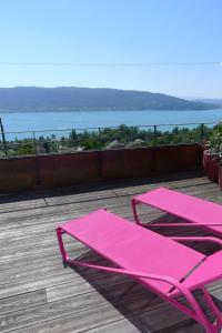 uma cadeira rosa e uma mesa num deque com vista em Le Clos Du Lac - location de chambres em Veyrier-du-Lac