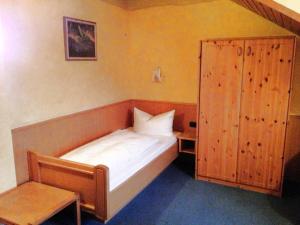 a small bedroom with a bed and a wooden cabinet at Beim Haxenwirt in Immenstadt im Allgäu