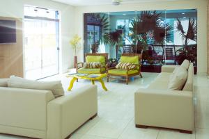 a living room with two white couches and a table at Pousada Jofisa Caraguá in Caraguatatuba