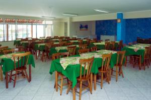 une salle à manger avec des tables et des chaises vertes dans l'établissement Pousada Jofisa Caraguá, à Caraguatatuba