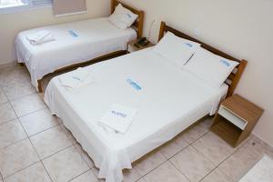 two beds with white sheets in a room at Pousada Jofisa Caraguá in Caraguatatuba +11 photos