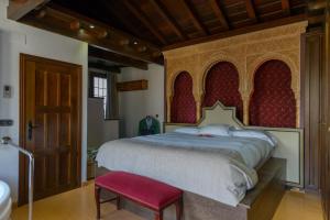 a bedroom with a large bed and a red chair at Casa del Beso in Granada