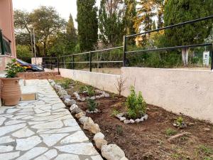 un giardino con passerella in pietra accanto a una recinzione di Ivy house modern life near Corfu town a Kontokali
