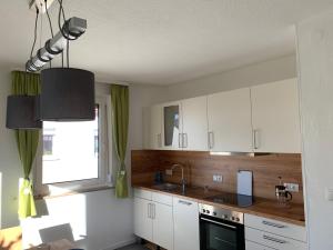 een keuken met witte kasten, een wastafel en een raam bij Ferienwohnung Fridolin in Bad Staffelstein