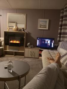 a person laying on a couch in a living room with a fireplace at The Trailer By The Sea in Millom