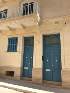 two blue doors on the side of a building at The Three Trees Apartments in Sliema
