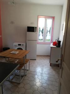 a kitchen with a table and a refrigerator and a window at Sweet garden in La Fère