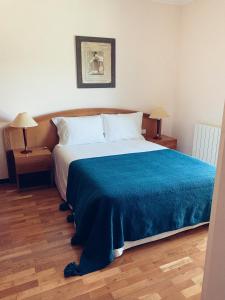 a bedroom with a large bed with a blue blanket at Casa Machado in Montalegre