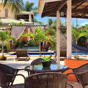 a patio with a table and chairs and a hammock at Mar de Guarajuba in Guarajuba