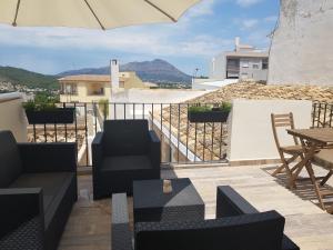 a balcony with chairs and tables and an umbrella at Casa Carol in Benitachell