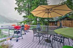 a deck with tables and chairs and an umbrella at Waterfront House with Glacial Views - Near Downtown! in Juneau