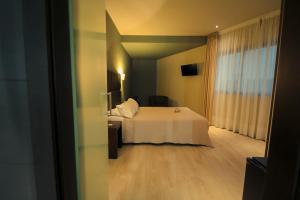 um quarto de hotel com uma cama branca e uma janela em Hotel Torre de Núñez em Lugo