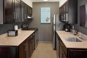 a kitchen with a refrigerator, sink, microwave and a counter top at Hyatt House Dallas Las Colinas in Irving