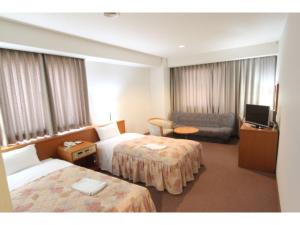 um quarto de hotel com duas camas e um sofá e uma televisão em SAIDAIJI GRAND HOTEL - Vacation STAY 92844 em Okayama