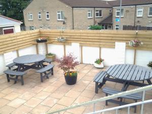 a patio with two picnic tables and a wooden fence at Lady Charlotte Guest rooms triple rooms in Dowlais