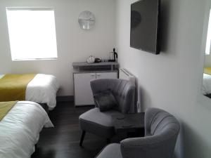 ein Hotelzimmer mit einem Stuhl und einem TV in der Unterkunft Lady Charlotte Guest rooms triple rooms in Dowlais