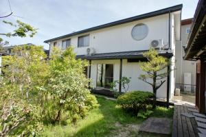 ein weißes Haus mit einem Garten mit Bäumen in der Unterkunft guest house Ki-zu - Vacation STAY 92940 in Nishio