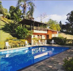 a swimming pool in front of a house at Sitio Arco Iris da Lia in São Roque