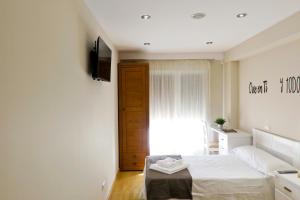 a bedroom with a bed and a television and a window at Habitaciones Albero in Toro